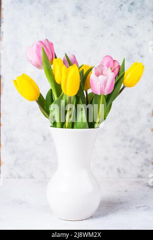 Tulpen Blumenstrauß in weißer Keramikvase auf hellem Hintergrund. Stockfoto