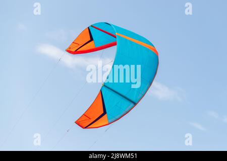 Nahaufnahme eine leuchtend blau orange Kitesurf Flügel Kite-Ausrüstung fliegen gegen klaren Himmel t an hellen sonnigen Tag gegen an Kiter Reiten Surfschule Stockfoto