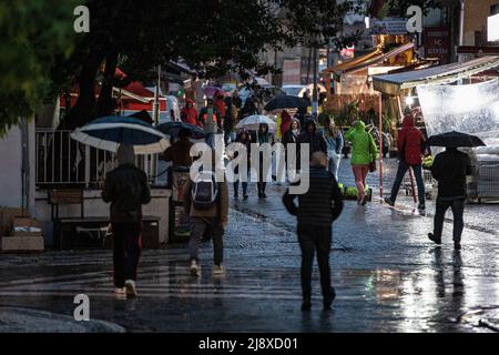 Istanbul, Türkei. 18.. Mai 2022. Die Leute sahen mit Sonnenschirmen während des Regens spazieren gehen. Im Istanbuler Stadtteil Acibadem im Stadtteil Kadikoy wirkte sich starker Regen, der in den Abendstunden plötzlich seine Intensität in und um die Ampel erhöhte, negativ auf das Leben aus. Einige wandelige Bürger und Kuriere hatten eine harte Zeit. Kredit: SOPA Images Limited/Alamy Live Nachrichten Stockfoto