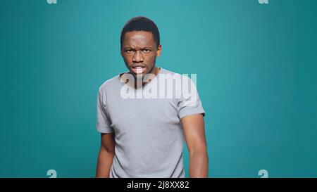 Gewalttätiger wütender Mann, der im Studio Wut und Aggression ausdrückt und vor der Kamera argumentiert. Unglückliche, aggressive Person, die Fäuste zusammenhält und frustriert ist, Konflikt-Uneinigkeit. Stockfoto