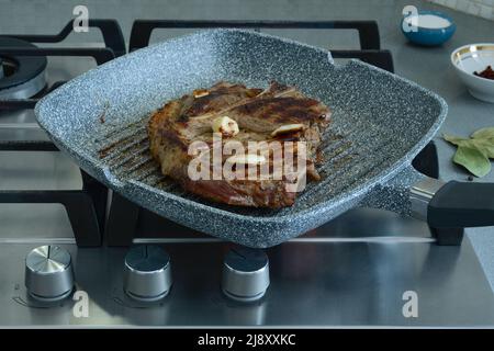 Stück Schweinefleisch auf dem Knochen, in einer Pfanne gebraten. Kochen von Fleisch in einer Pfanne in einer heimischen Küche Stockfoto
