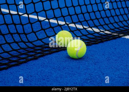 Blick auf zwei Kugeln in der Nähe des Netzes eines blauen Kunstrasen Paddel Tennisplatz. Stockfoto