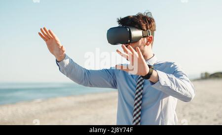 Geschäftsmann mit Augmented-Reality-Viewer am Metaverse-Strand Stockfoto