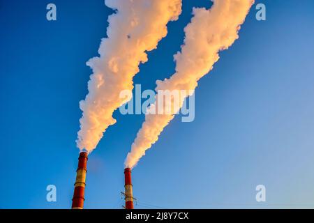 Weißer Rauch kommt aus den Rohren am blauen Himmel Stockfoto