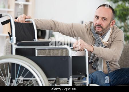 Mann im Rollstuhl versucht, alleine zu sitzen Stockfoto