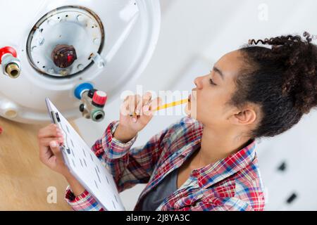 Weibliche Klempner Arbeiten an zentralen Heizkessel Stockfoto