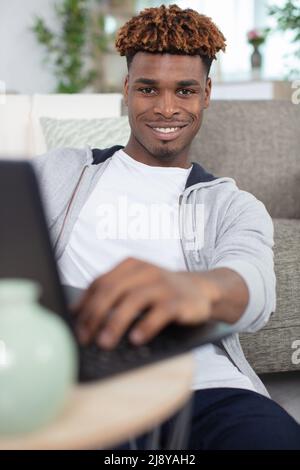 Glücklicher Mann benutzt den Laptop Stockfoto