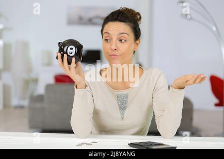 Frau, die versucht, Geld aus dem Sparschwein zu bekommen Stockfoto