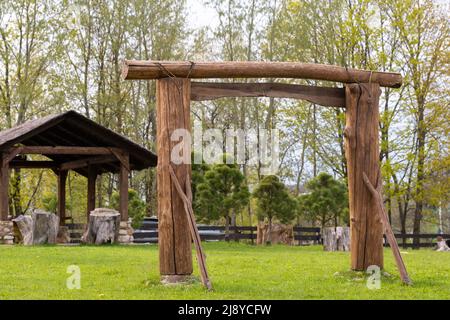 Ein Holzbogen und ein Holzpavillon stehen auf dem Gebiet neben dem Anwesen. Stockfoto