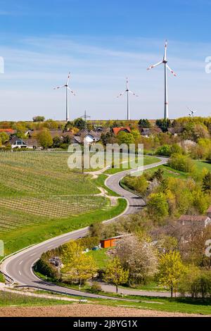 Kurvenreiche Straße, die zu einer ländlichen Siedlung führt, die in Deutschland von Windenergieanlagen dominiert wird Stockfoto