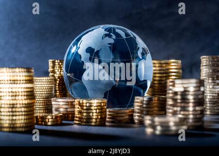 Globe und Stapel mit Münzen. Geld lässt die Welt umrunden Stockfoto