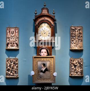 Christie’s, London, Großbritannien. 19 Mai 2022. Christie’s wird am 25. Mai in einer Live-Auktion die Sammlung von Sir Nichola Goodison - British Art: Innovation and Craftsmanship anbieten. Bild: Gruppe von Alabasterreliefs, Ende des 15.. Jahrhunderts - neutestamentliche Geschichten. Schätzung (unten rechts) £40.000-60.000. Christies Art Handler hält eine SIR EDWIN HENRY LANDSEER, R.A. (1802-1873), Portrait of Catherine Seyton, Schätzung £12.000-18.000 vor einer John Ellicott, London, um 1740 George II markante Langkoffuhr mit Barometer. Schätzung: £40.000-60.000. Quelle: Malcolm Park/Alamy Live News. Stockfoto