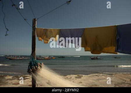 Wäscherei- und Fischernetz im Hintergrund von Fischerbooten und Indischem Ozean, fotografiert am Malabero (Malabro) Strand in Bengkulu, Indonesien. Stockfoto