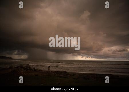 Stürmische Regenwolken und Niederschläge über dem Indischen Ozean sind von einem Strand in Bengkulu, an der Westküste von Sumatra, Indonesien, zu sehen. Stockfoto