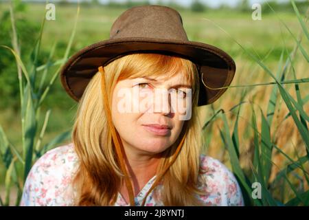 Unschärfe Nahaufnahme außerhalb Porträt der schönen jungen blonden Frau auf Natur Hintergrund. Schatten der Pflanzenkunst. Cowgirl auf der Wiese. Psychische Gesundheit, Stille. C Stockfoto