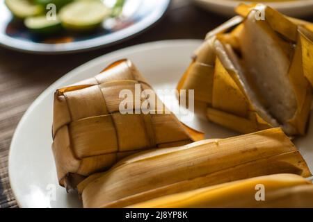 Reiskuchen (Ketupat) wird gekocht Reis verpackt in einem diamantförmigen Behälter aus geflochtenem Palmblatt-Beutel für die Moslem-Geburtstagsfest. Eid Mubarak Konzept. Indo Stockfoto