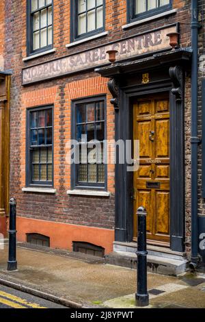 Spitalfields London - Georgisches Haus in der Princelet St im Spitalfields-Naturschutzgebiet im Osten Londons, mit Geisterzeichen für das moderne Saree Centre. Stockfoto