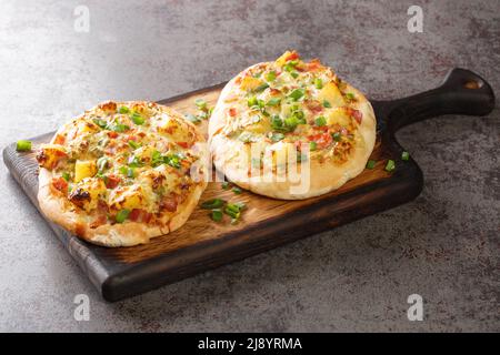 Deutsche Pizza-tart Flambee Schwäbische Dinnete mit Kartoffeln, Zwiebeln und Speck aus der Nähe auf einem Holzbrett auf dem Tisch. Horizontal Stockfoto