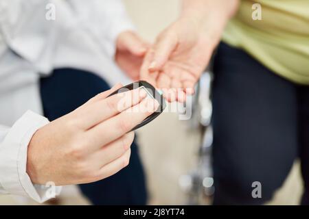 Arzt oder Krankenschwester, die Diabetes mit dem Messgerät am Finger des Patienten überprüfen Stockfoto