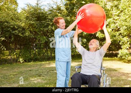 Physiotherapeut und Senior im Rollstuhl trainieren mit Gymnastikball für die Mobilität nach einem Schlaganfall Stockfoto