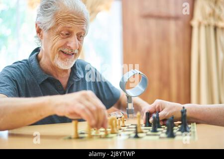 Senior spielt Schach im Altersheim oder zu Hause für Konzentration und Strategie Stockfoto