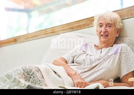 Alte kranke Frau im Schlafanzug als Patientin liegt im Bett im Krankenhaus oder im Altersheim Stockfoto