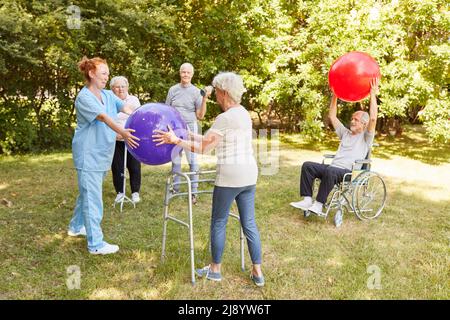 Gruppe von Senioren mit Behinderungen machen Übung mit Gymnastikball für die Mobilität in Reha-Klasse Stockfoto