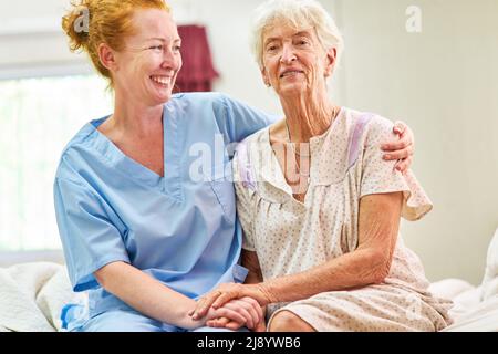 Fürsorgliche geriatrische Krankenschwester umarmt und tröstet alte Frau im Pflegeheim oder Krankenhaus Stockfoto