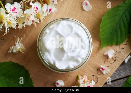 Ein Glas Salbe aus frischen Rosskastanienblüten auf einem hölzernen Hintergrund, Draufsicht Stockfoto