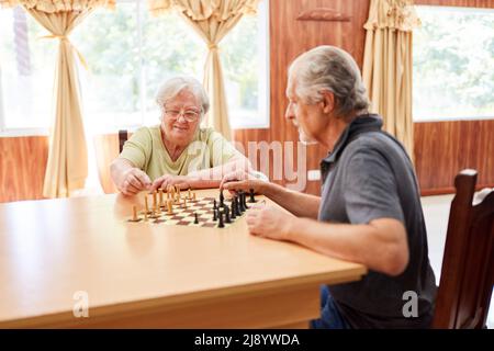 Ein paar Senioren spielen Schach zusammen mit Konzentration als Gedächtnistraining im Pflegeheim Stockfoto
