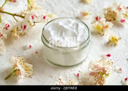 Ein Glas Salbe oder Creme aus frischen Rosskastanienblüten in einem Glas auf einem hellen Hintergrund Stockfoto