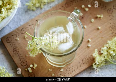 Limonade mit Sirup aus frischen Holunderblüten im Frühjahr in einem Glas mit Eis Stockfoto