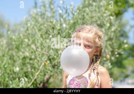 Nettes Mädchen mit blonden Haaren, das Spaß mit Kaugummi hat Stockfoto