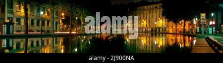 Bassin des Récollets mit Blick nach Süden auf den Kanal Saint-Martin bei Nacht, mit l’Hôtel du Nord, quai de Jemmapes, passerelle d’Hôtel du Nord und quai de Valmy. Stockfoto