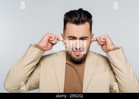 Unzufriedener Kritiker verstopfte Ohren mit Fingern, die auf Grau isoliert waren Stockfoto