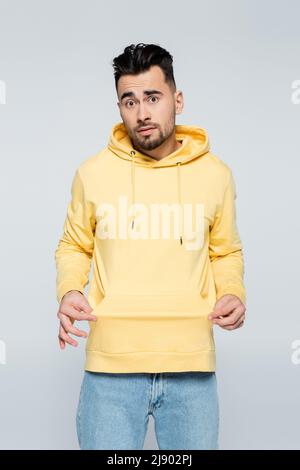 Verwirrt Spieler zeigt leere Tasche isoliert auf grau Stockfoto