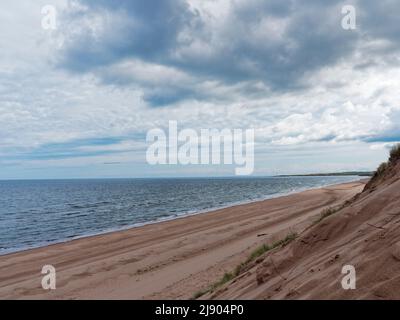 Ein leerer Montrose Beach und Bay nach einem Regen mit dem Sand einer tieforangefarbenen Farbe und dunklen Wolken über den Heralding Further Showers. Stockfoto