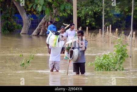 Nagaon (Assam) 19. Mai 2022: Dorfbewohner watten durch Hochwasser, als die Straße von Nagaon nach Kampur am Donnerstag im Dorf Kathiatoli im Bezirk Nagaon von Assam in Hochwasser getaucht war. Foto von DIGANTA TALUKDAR/ ALAMY LIVE NEWS Stockfoto