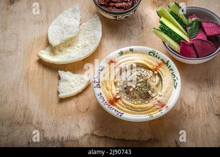 Kichererbsen-Hummus mit Olivenöl und geräuchertem Paprika mit Gurke und Rettich Stockfoto