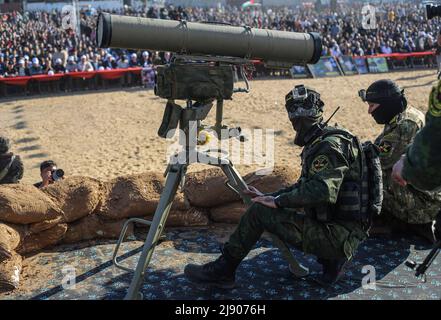 Gaza, Palästina. 18.. Mai 2022. Palästinensische Kämpfer versammeln sich um eine "Kornetkanone", die auf der Bühne einer Kundgebung anlässlich des ersten Jahrestages des Konflikts zwischen Israel und Gaza am 2021. Mai in Beit Hanun im nördlichen Gazastreifen gezeigt wird. Kredit: SOPA Images Limited/Alamy Live Nachrichten Stockfoto