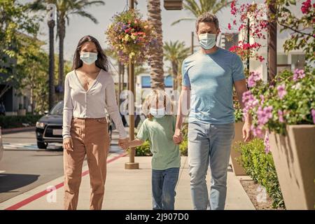 Eltern mit Kind Junge tragen medizinische Maske. Mama Vater und Sohn. Lebensversicherung. Adoption und Nächstenliebe. Stockfoto