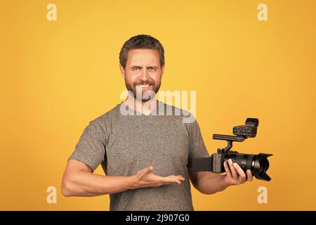 Glücklicher bärtiger Videofilmer, der professionelle Camcorder und Produktvorschläge vorstellt Stockfoto