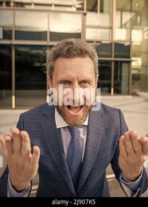 Fröhlicher emotionaler bärtiger Geschäftsmann in formellem Anzug, gestikulend, emotional Stockfoto