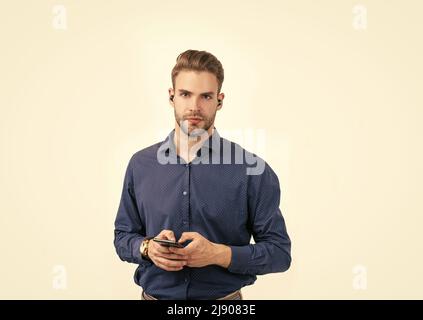 Neue Technologie. Unrasiert Kerl Typ Nachricht. Online-Geschäft. Mann mit drahtlosen Kopfhörern und Telefon. Stockfoto