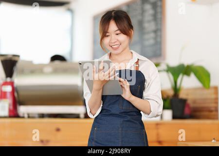 Porträt des asiatischen Barista Café Besitzer mit Tablet, um die Bestellung zu überprüfen. KMU Unternehmer Verkäufer Geschäftskonzept. Stockfoto