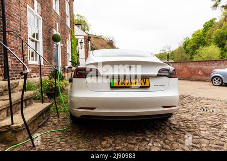 Tesla, Tesla-Auto, Tesla-Autoladung, Tesla-Elektroauto, Auto eingesteckt, Tesla-Elektroauto, Tesla-Autoladegerät, Autoladegerät, Autoladung, Auto an das Stromnetz angeschlossen Stockfoto