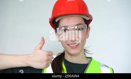 Eine junge, schöne, glückliche Bauarbeiterin zeigt sich begeistert Stockfoto