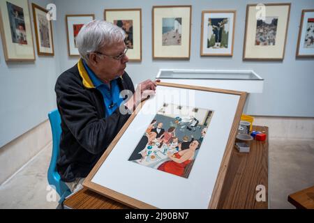 London, Großbritannien. 19 Mai 2022. Ein Mitarbeiter bereitet sich darauf vor, „The Right Spirit - [Dinner is served]“, 1938, von William Heath Robinson bei einer Vorschau vor der neuen Ausstellung „The Humor of William Heath Robinson“ im Heath Robinson Museum in Pinner, Nordwesten Londons, aufzuhängen. Die Ausstellung, die vom 21. Mai bis zum 4. September 2022 stattfindet, feiert das Werk des Künstlers und am 31. Mai 2022 den 150.. Geburtstag seines Künstlers. Kredit: Stephen Chung / Alamy Live Nachrichten Stockfoto