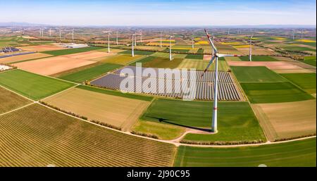 Riesige Windturbinen zwischen landwirtschaftlichem Land und einem Solarpark in einer ländlichen Gegend aus Drohnensicht, Deutschland Stockfoto