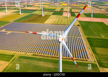 Riesige Windturbinen zwischen landwirtschaftlichem Land und einem Solarpark in einem ländlichen Gebiet aus Drohnenperspektive, Deutschland Stockfoto